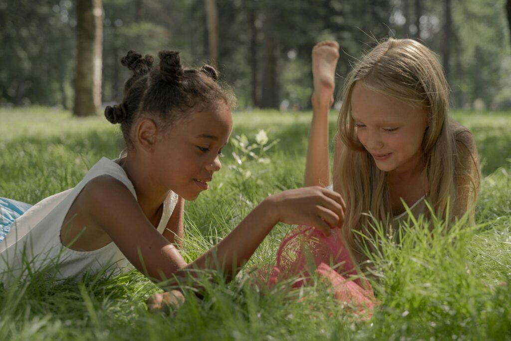 pexels-photo-10601645-10601645 Two girls enjoying a playful moment in a sunny park surrounded by lush green grass.