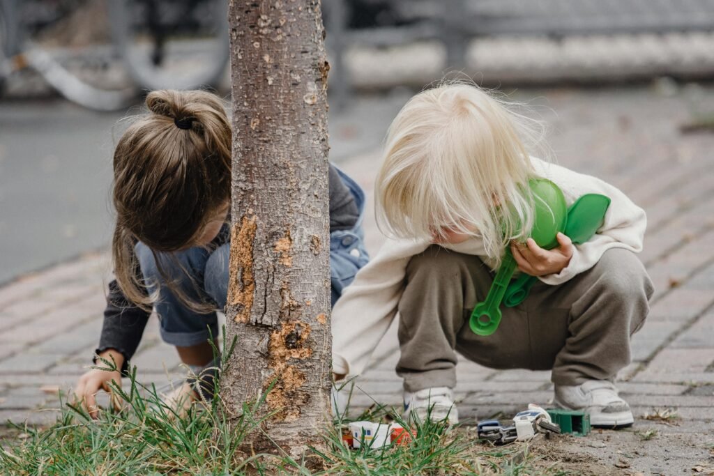 pexels-photo-5622398-5622398 Full body of anonymous cute little girls in casual outfits playing with toys near tree